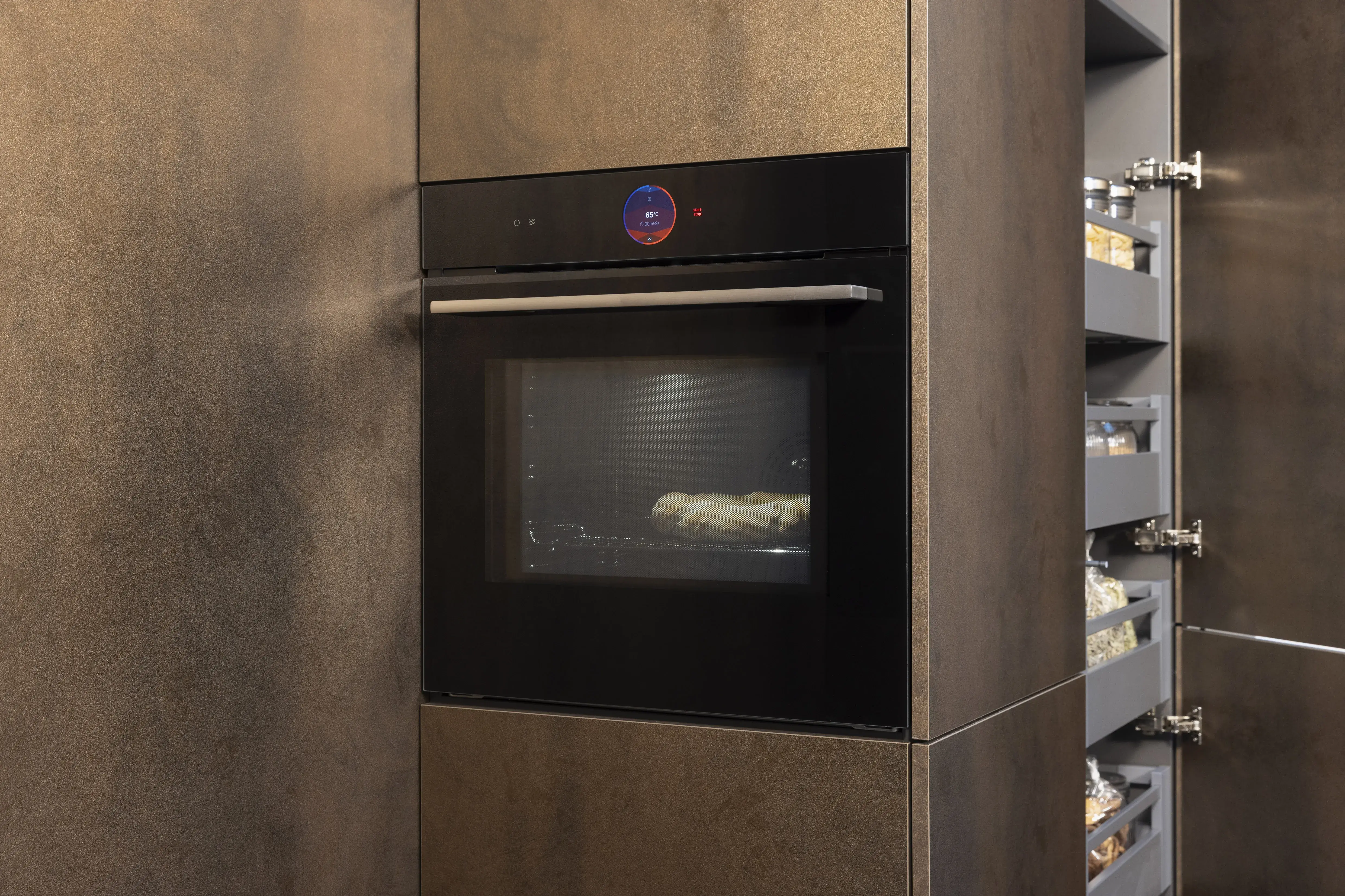 Moderne Einbauküche mit Backofen; im Ofen brät ein Baguette.