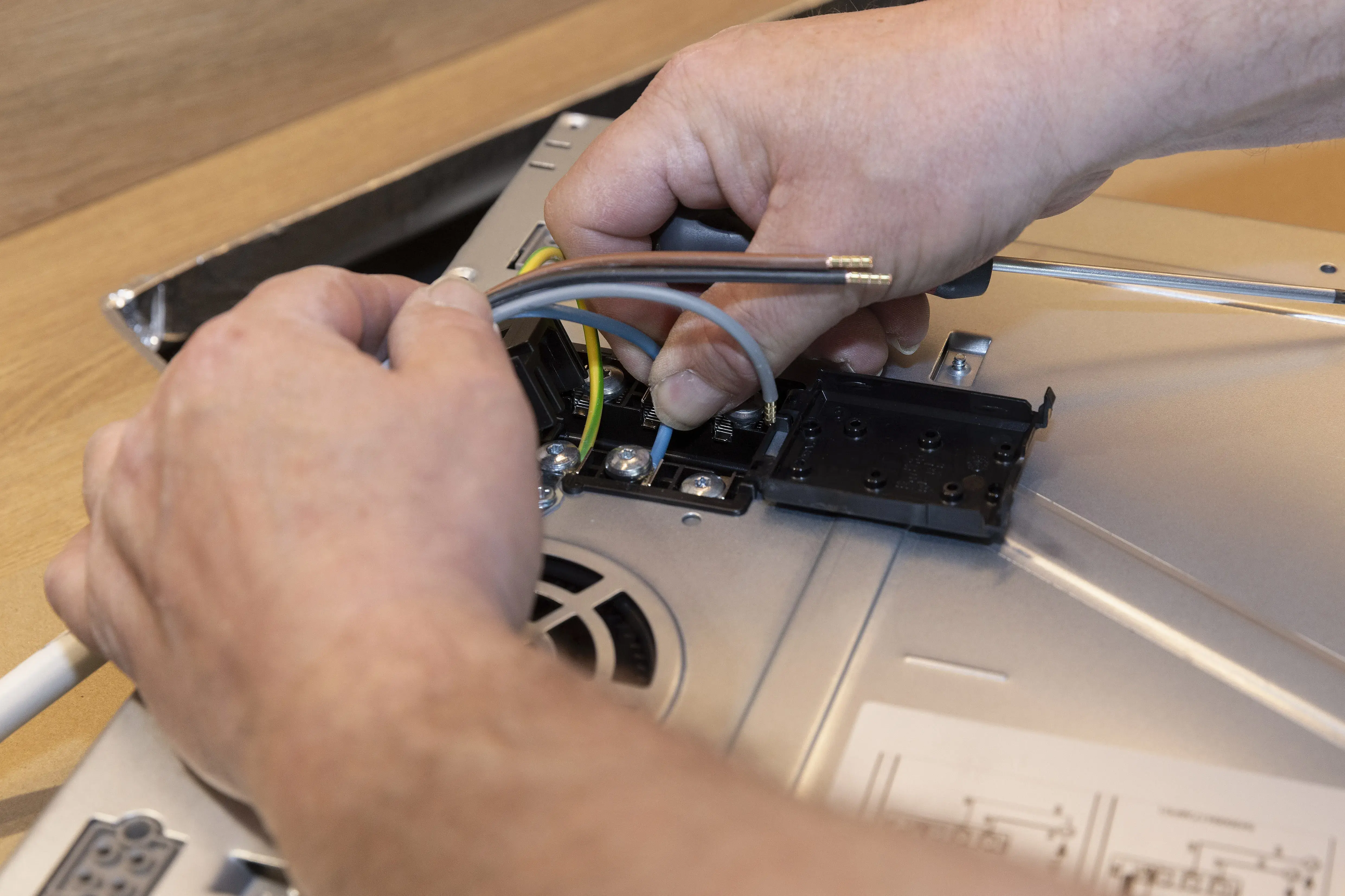 Hände schließen Kabel an ein elektrisches Gerät an.